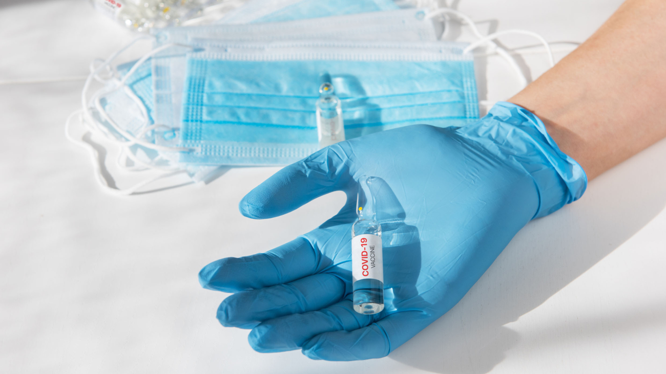 Coronavirus vaccine concept: covid-19 vaccine in hand with blue protective gloves.