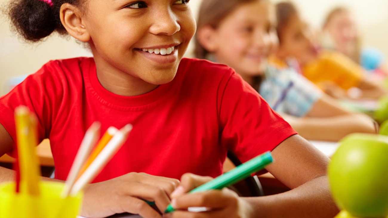 Row of pupils looking at teacher with cute girl in front